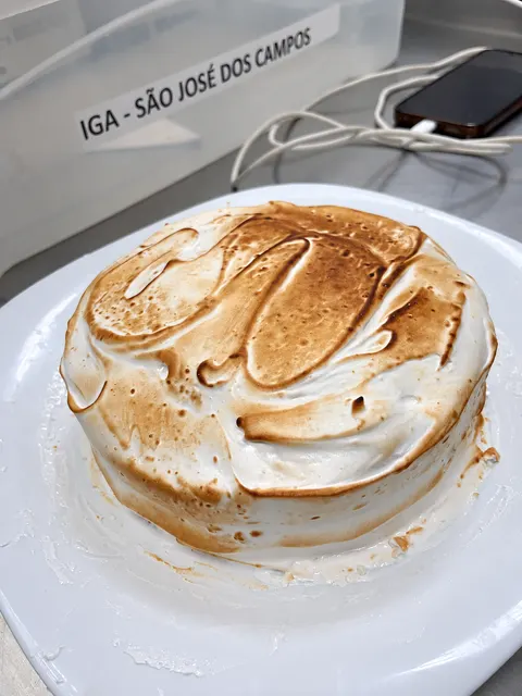 Um bolo com cobertura dourada, na bancada do IGA.
